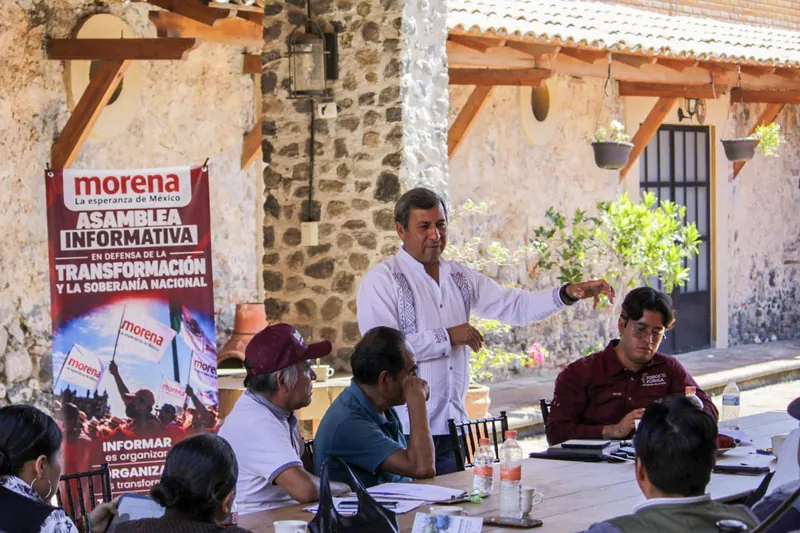 El General Arturo Solano platica con vecinos en una mesa.